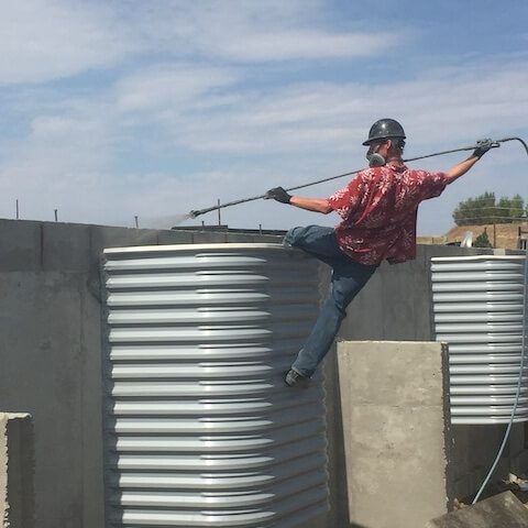 Man working on concrete walls spraying solution