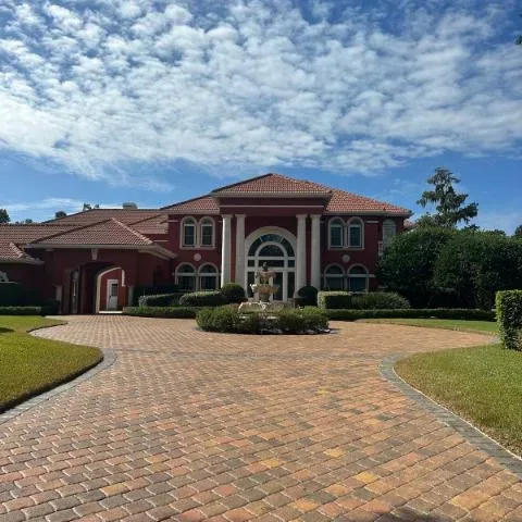 a brick walkway with sealer on it and a home in the background